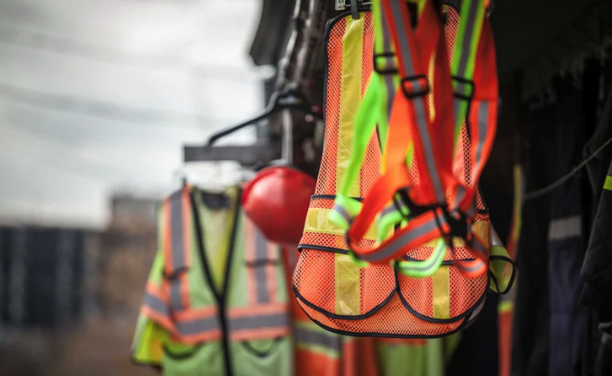 Używana odzież ostrzegawcza hi-vis, buty i rękawice robocze wiszące na wieszaku na budowie